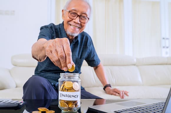 Image of a senior man, adding coins to his emergency fund.