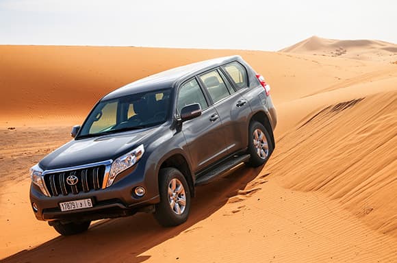 Image of a used SUV, driving in the middle of the desert.
