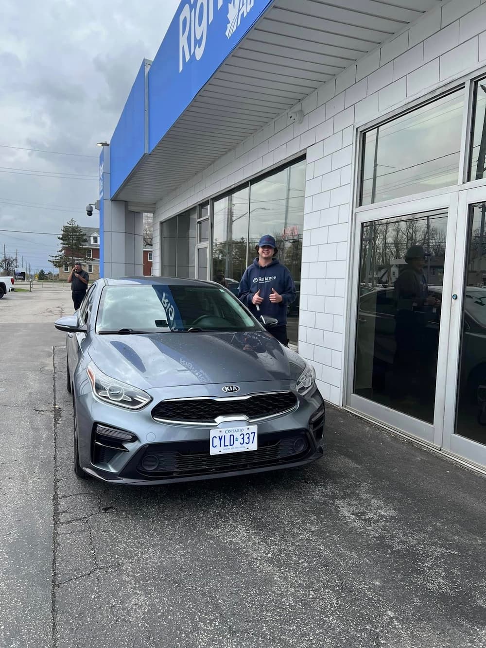 Image of a happy customer and their new car in front of the RightRide dealership.