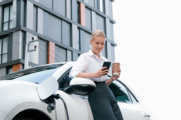 Image of a customer, enjoying her coffee while charging her electric vehicle from RightRide
