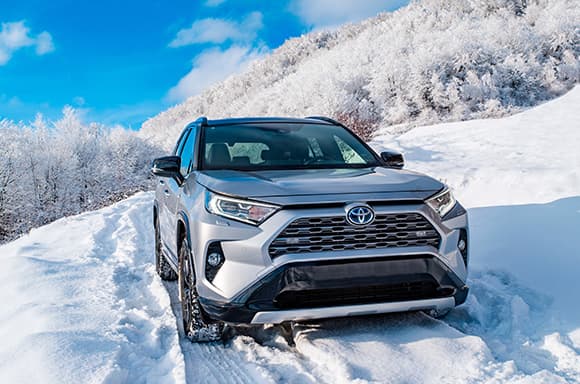 Image of a used Toyota Rav4 SUV, driving up a winter road.