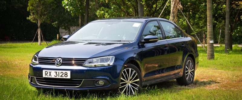 Image of a navy blue Volkswagen Jetta, parked outside on a field.