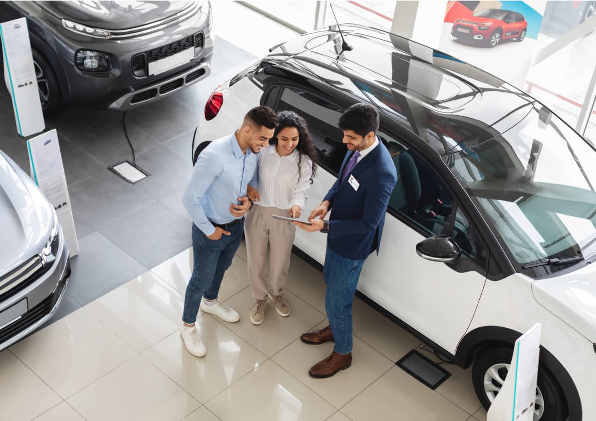 Employee reviewing a contact inside a dealership with potential buyers.