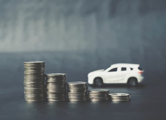 Toy car placed behind a stack of coins to represent car equity.