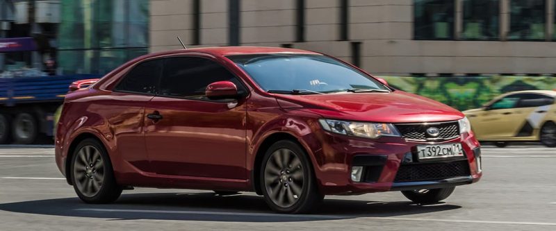 Image of a red Kira Forte cruising down the street.