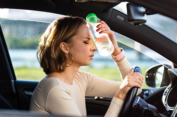 Image of a driver, using a water bottle to cool down from driving in warm climate.