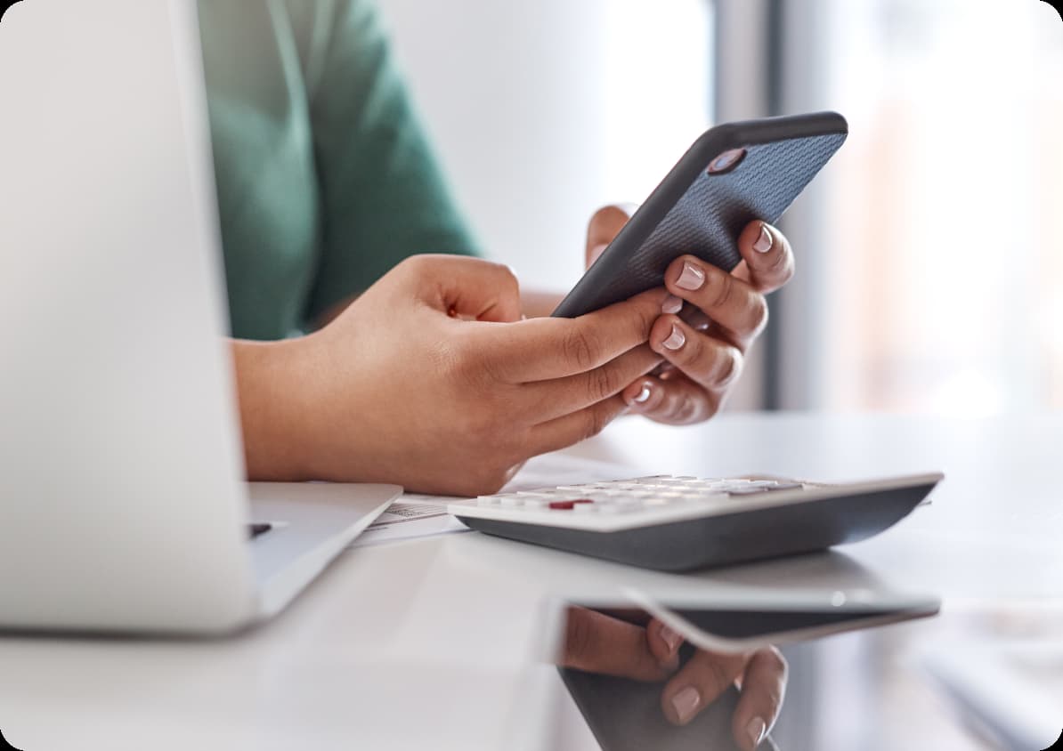 Woman using smartphone at her computer.