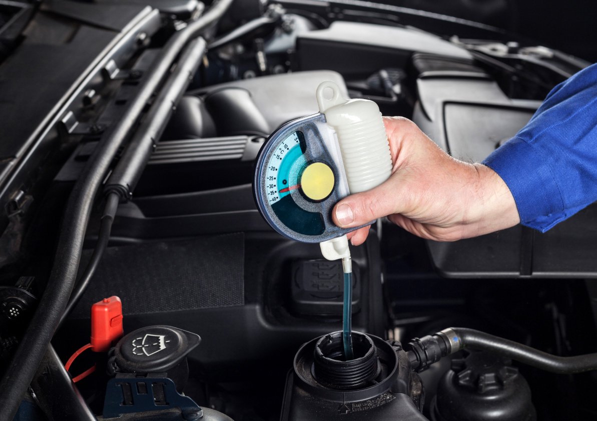 Mechanic checking the oil of a vehicle with a tool.