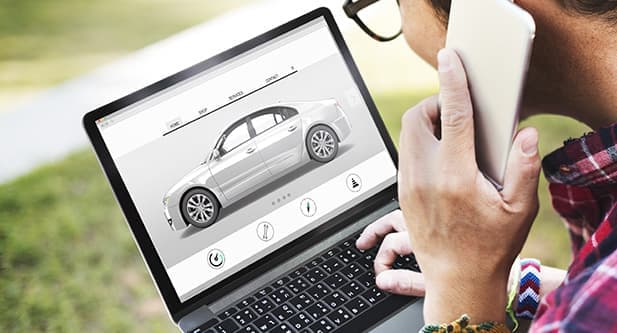 Image of a person doing vehicle research on laptop, while talking on the phone.