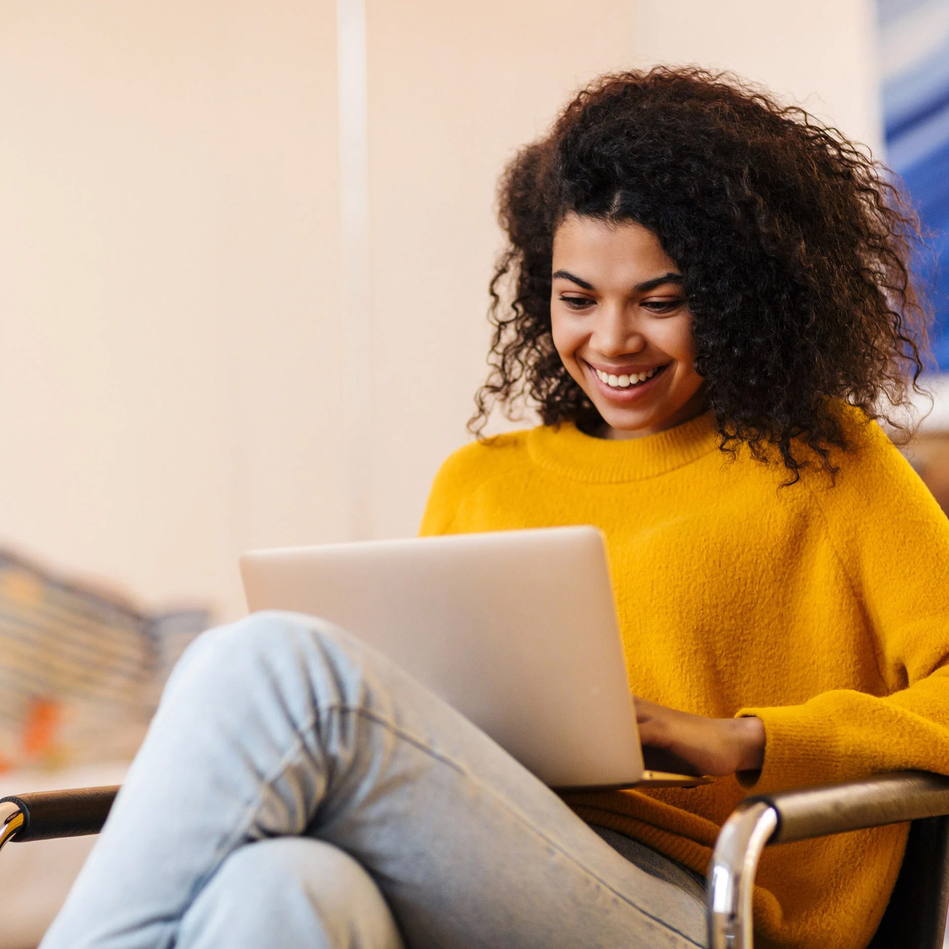 Young woman smiling while looking at her laptop.