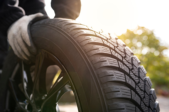 Image of a mechanic rolling a winter tire.