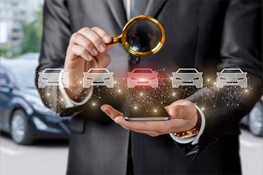 Image of a person holding a magnifying glass, to reflect vehicle research.