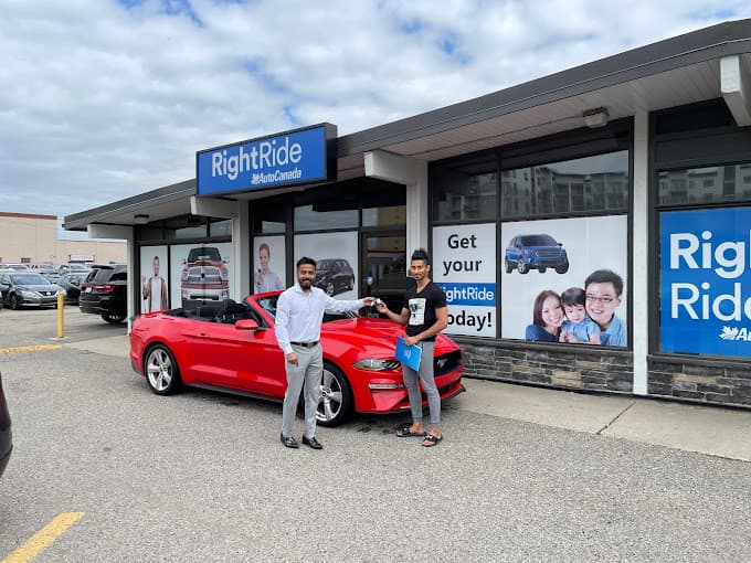 Happy customer with a new red car outside of RightRide location.