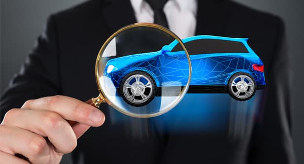 Image of a person wearing a suit, holding a magnifying glass up close to a vehicle hologram.