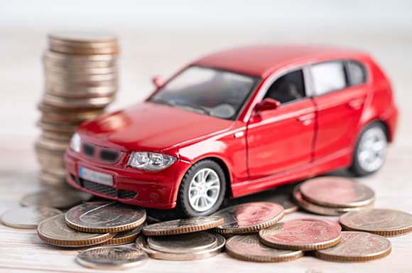Image of a toy car, placed beside a stack of coins.