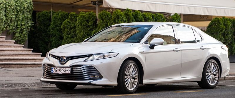 Image of a white Toyota Camry parked outside on the street.
